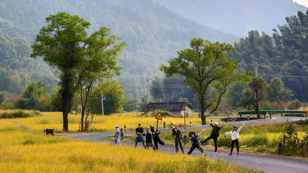 Huangshan rural road with digital nomads, golden fields, trees, and mountain scenery