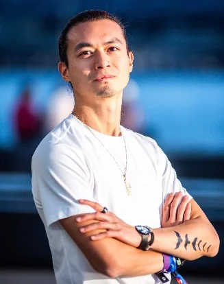 Life coach Freeman Fung standing with arms crossed at a waterfront harbour at golden hour