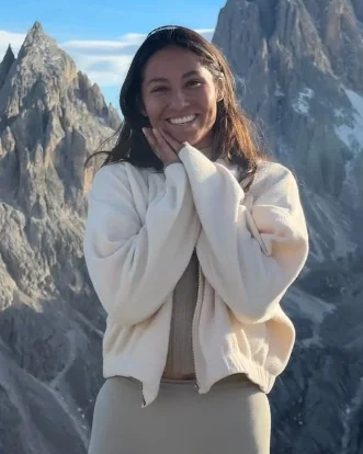 Digital nomad coach Lis Kanzler smiling in front of jagged snow-capped mountain peaks