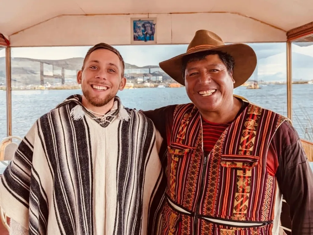 Igor Kondrat smiling with a local guide on a boat on Lake Titicaca, Peru