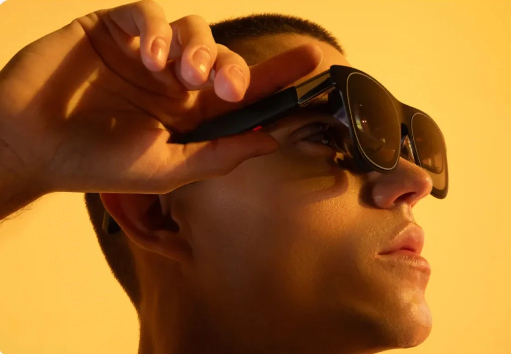 Person wearing Xreal One augmented reality glasses in warm studio lighting
